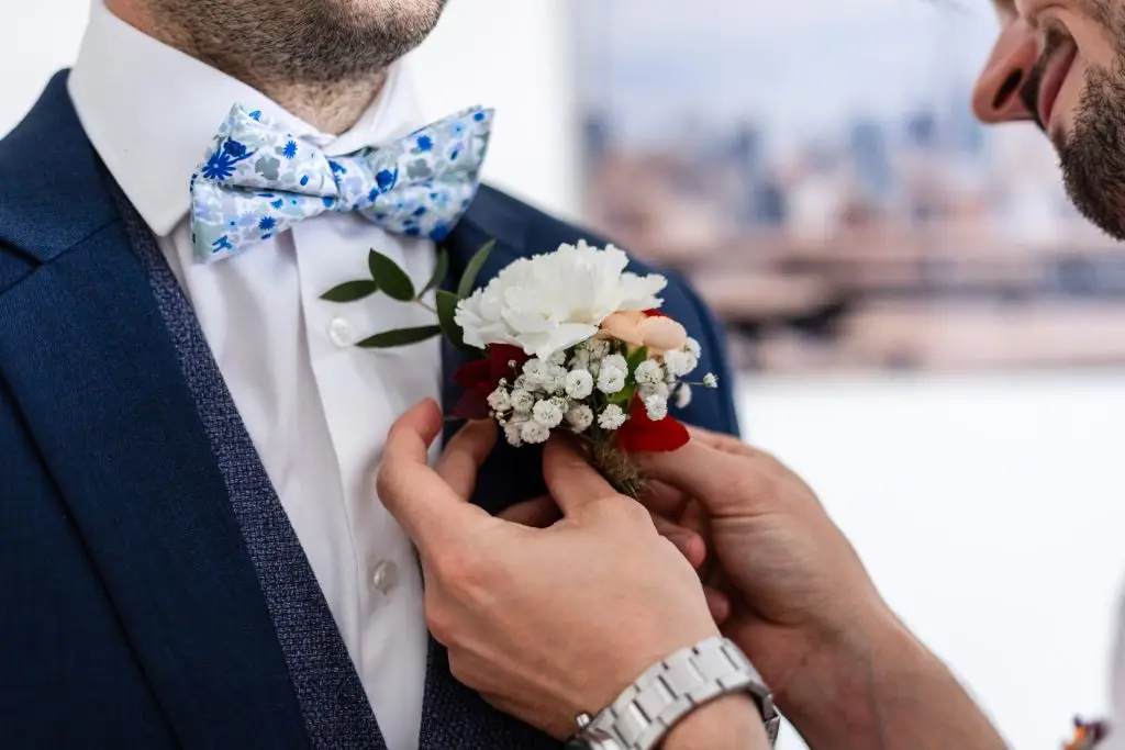 Un ami du marié épingle la composition florale à la veste du marié.
