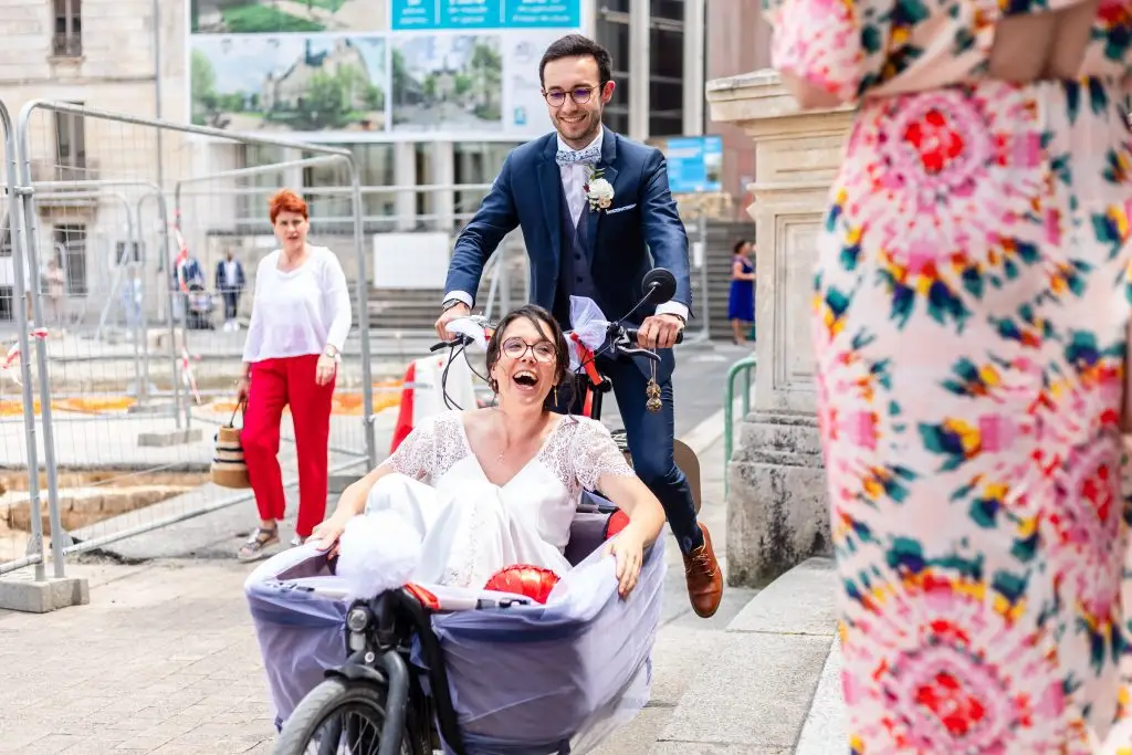 Les mariés s'échappent en riant de la cérémonie civile en vélo et cariole.