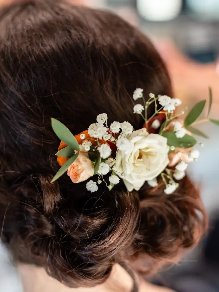 Détails de la coiffure de la mariée avec les fleurs dans ses cheveux.