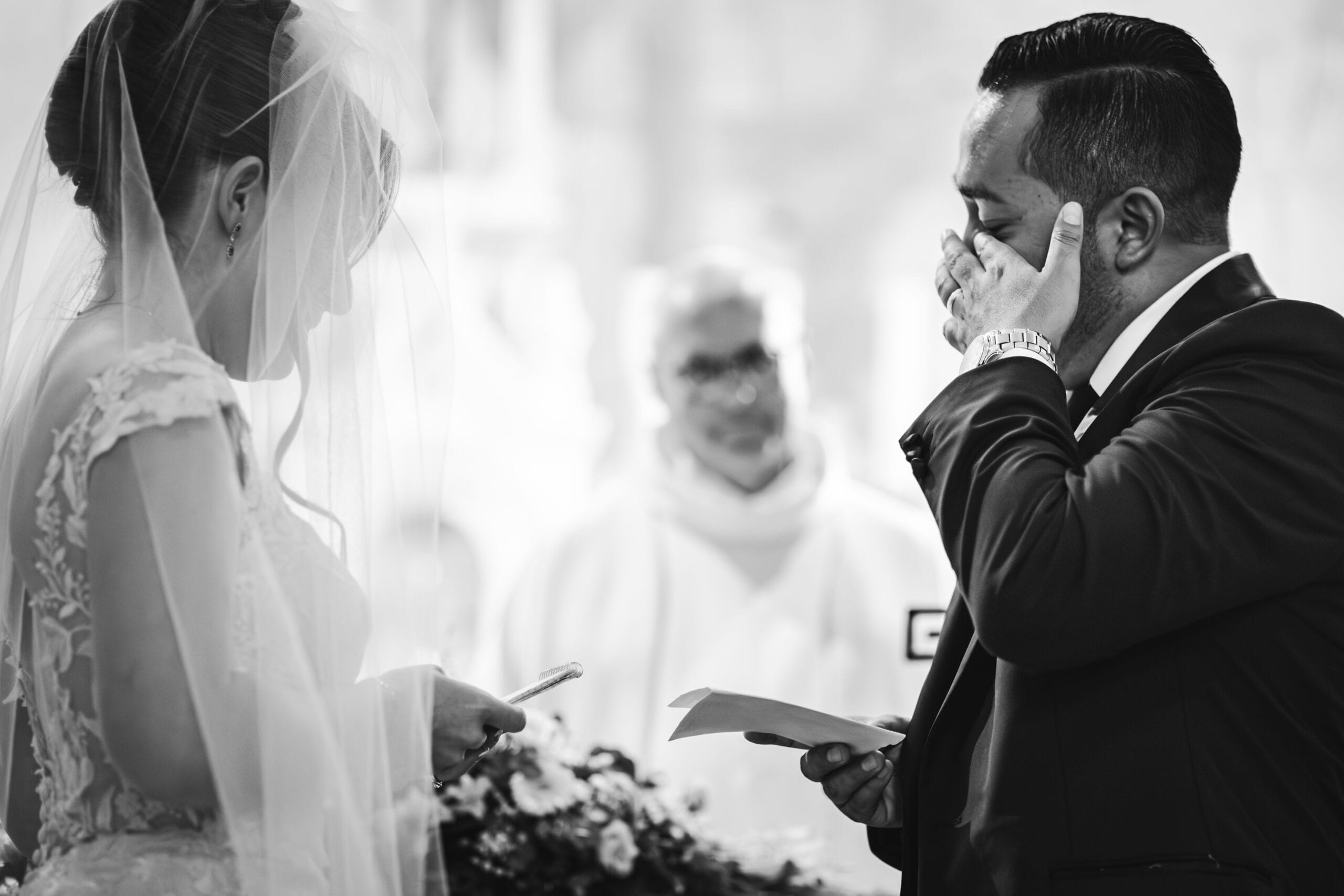 Pendant la cérémonie religieuse et l'échange des voeux, le marié essuie une larme qui perle au coin de son oeil.