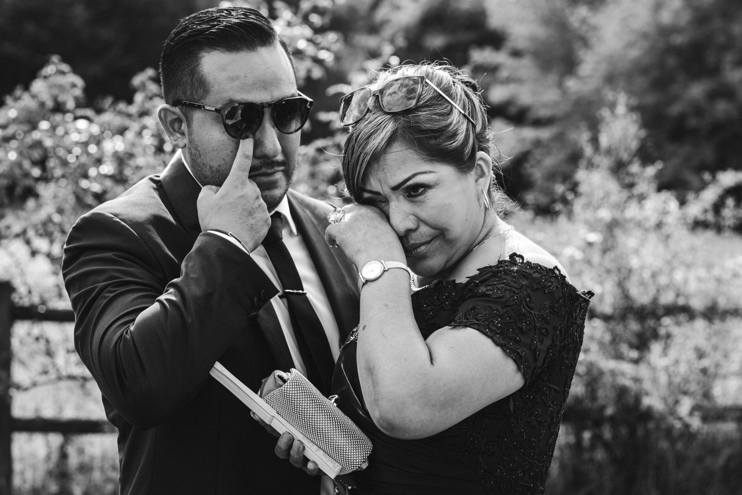 Le marié et sa mère essuient simultanément des larmes d'émotions qui perlent aux coins de leurs yeux, par une photographe mariage Landes.