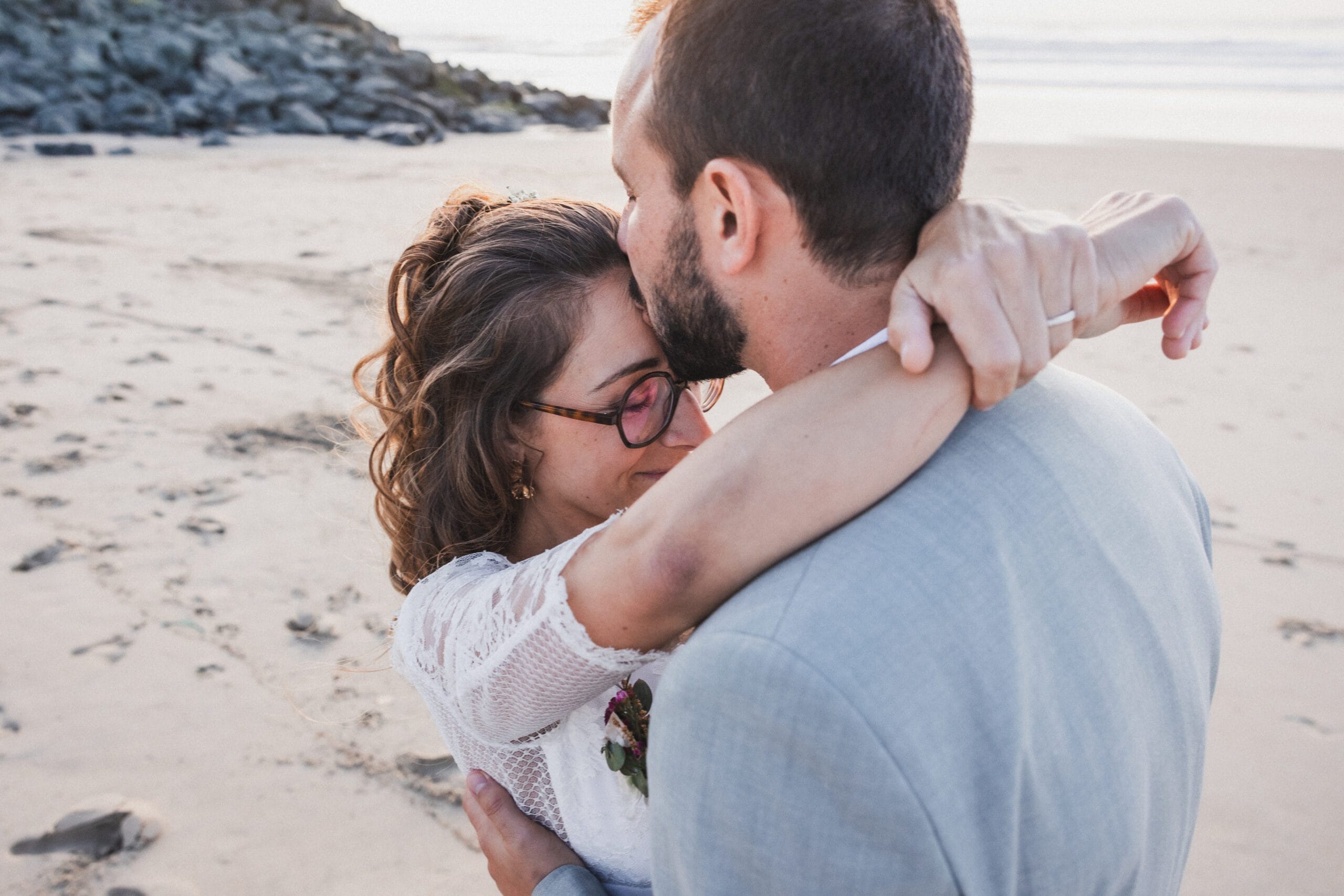 Le marié embrasse sa femme sur le front pendant la séance couple sur la plage à Anglet, Pays Basque