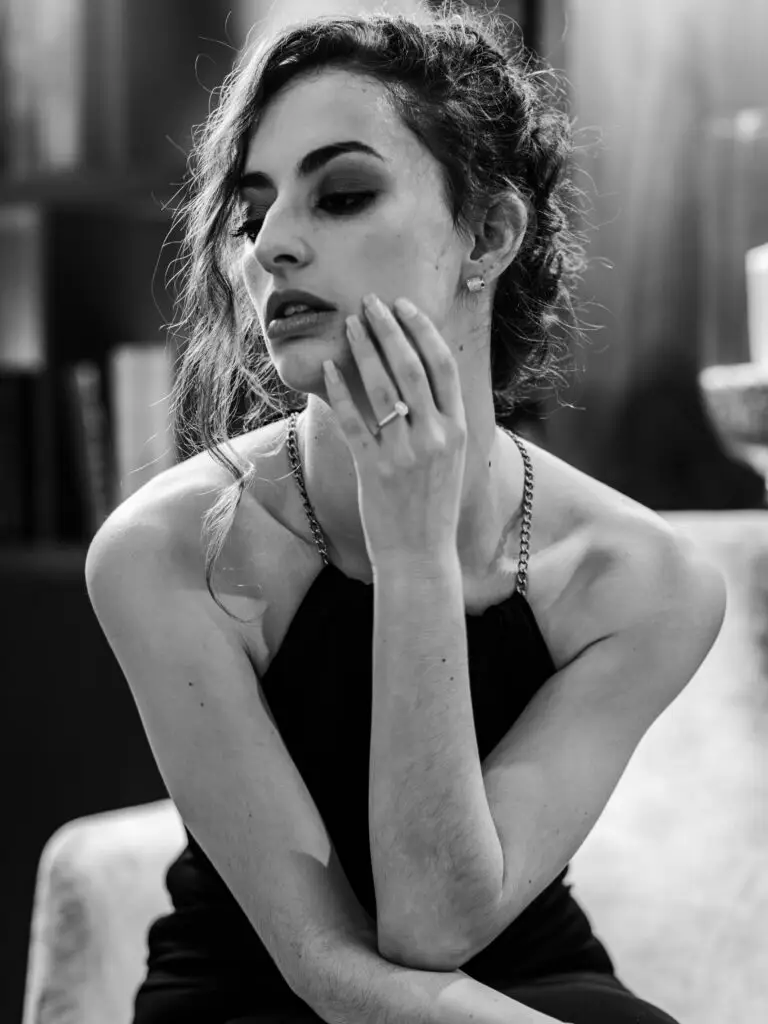 La modèle prend la pose assise dans la salon lounge et met en avant la bague à son annulaire