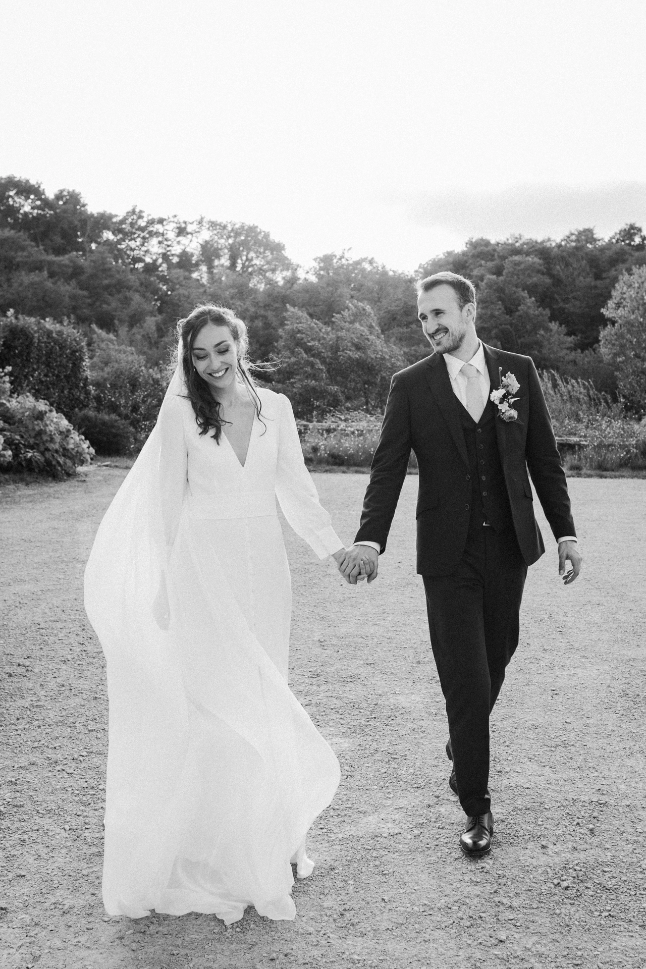 Pendant la séance couple, les mariés marchent main dans la main en souriant, lors de leur mariage dans les Landes.