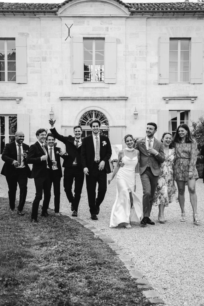 Pendant la séance photo de groupe, les mariés et leurs témoins marchent vers la photographe de mariages colorés en riant