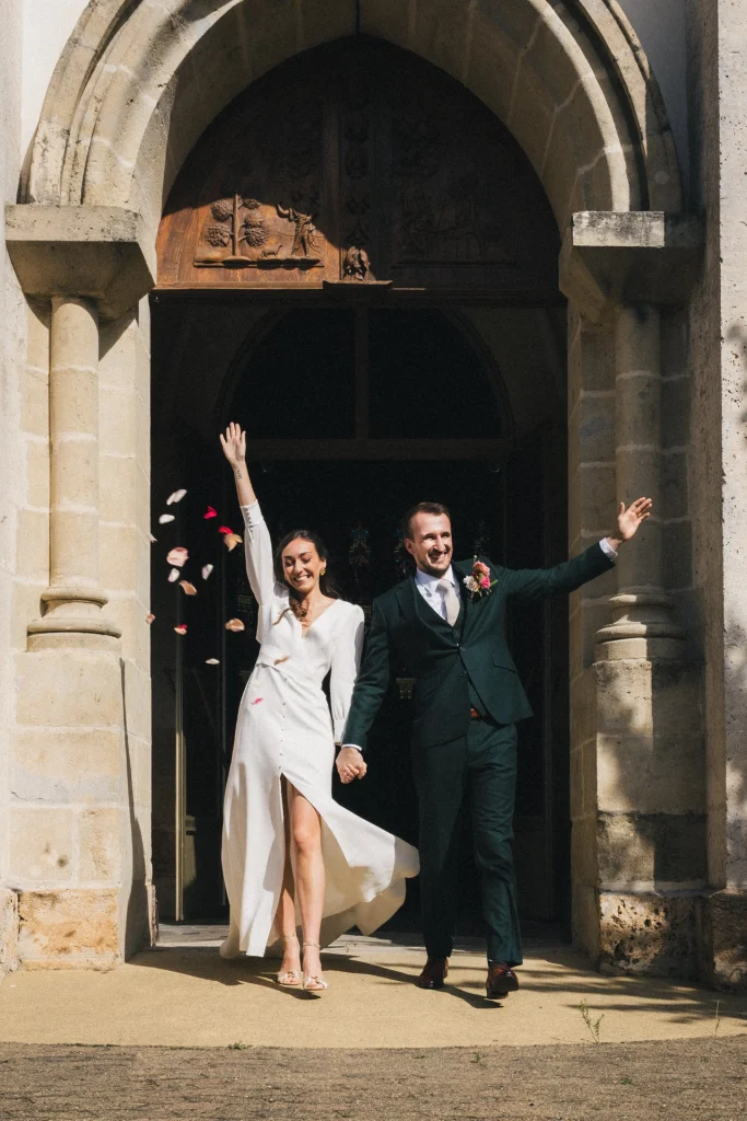 Sortie de cérémonie religieuse dans les Landes, les mariés sont heureux et lèvent les bras en signe de triomphe.