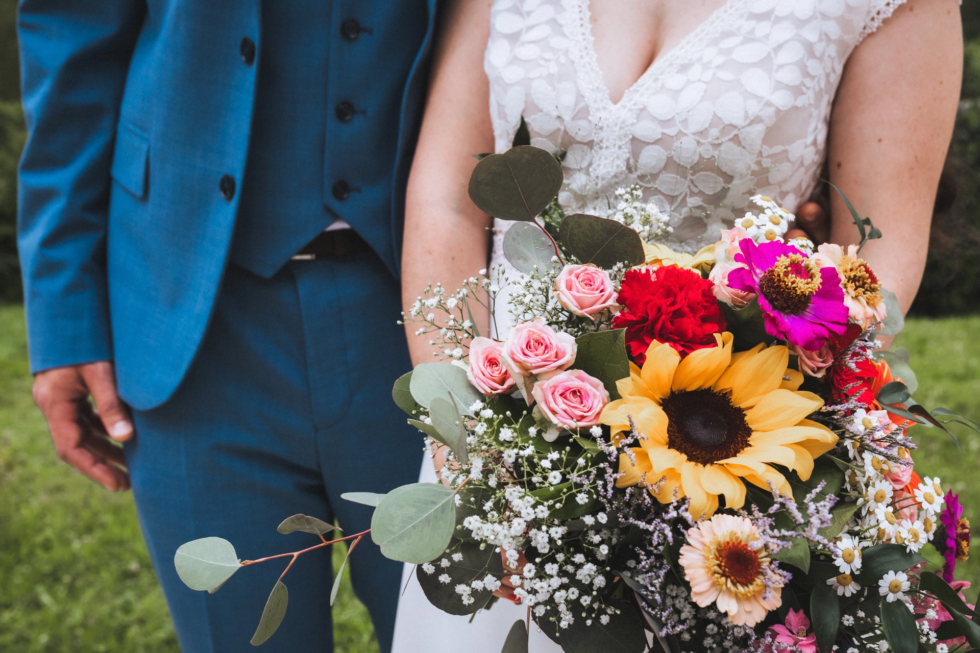 Détail du bouquet de fleurs de la mariée, qui se tient au côté de son futur mari. Les couleurs sont pétillantes.