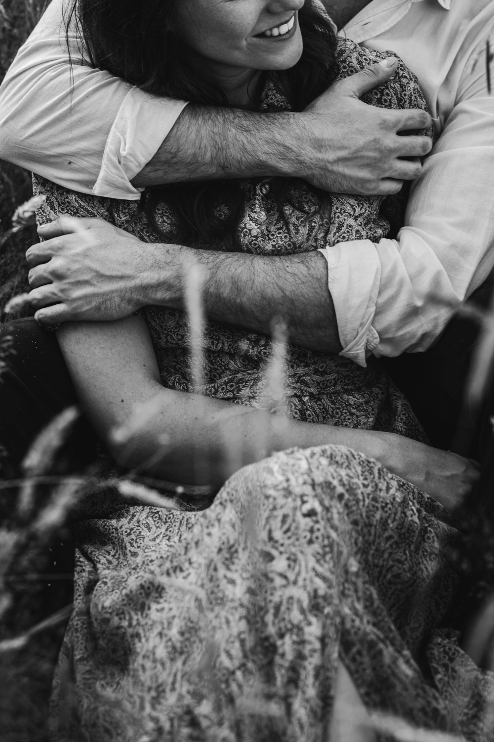 Lors de la séance fiançailles, le couple se tient enlacer dans un champ.