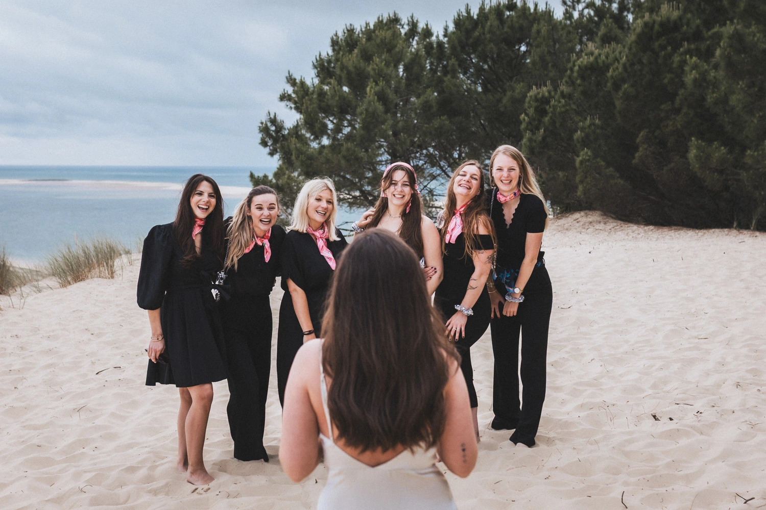 La future mariée se tient de dos, face à ses amies habillées en robes noires, lors de son enterrement de vie de jeune fille.
