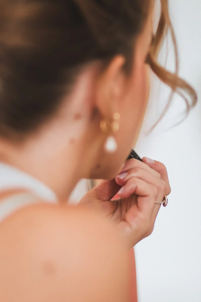 Préparatifs de la mariée au château Larteau en Gironde, qui peaufine son maquillage avec une touche de rouge à lèvres.