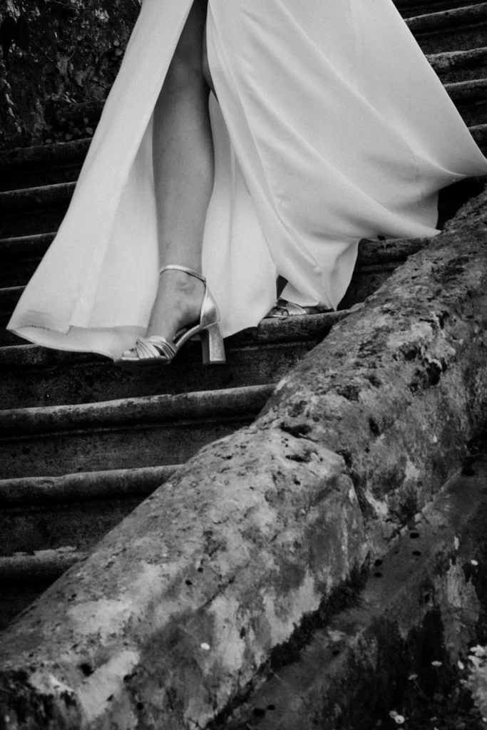Détail de la jambe de la mariée, à travers la fente de sa robe, qui descend l'escalier du Château de Campet dans les Landes.