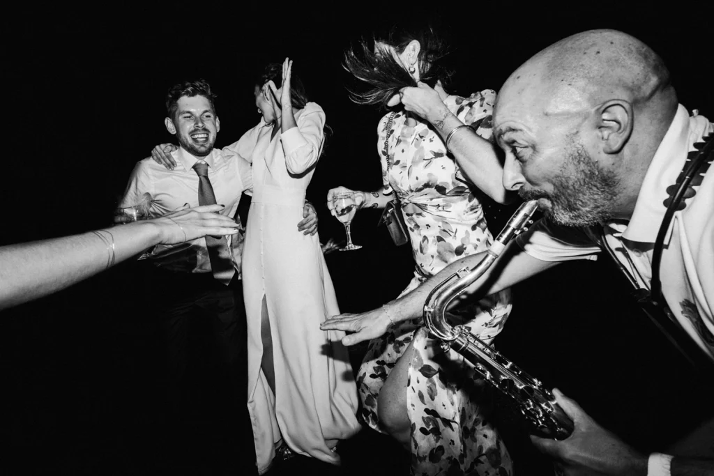 Scène de cocktail où la mariée et ses invités dansent de manière endiablée au son du saxophone.
