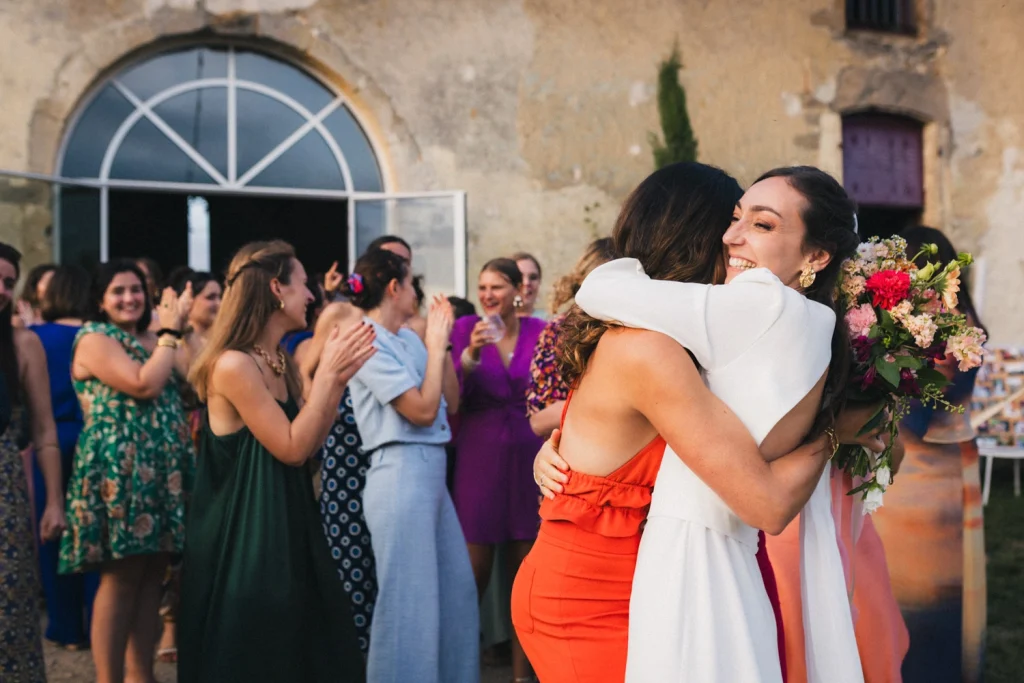 Après le lancer de bouquet, la mariée serre son amie qui a gagné les fleurs dans ses bras.