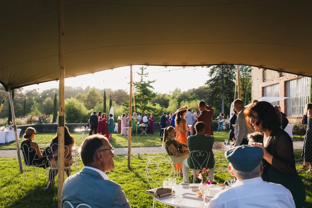 Scène de cocktail paisible lors d'un mariage dans les Landes, où les invités discutent tranquillement alors que la lumière du jour décline.
