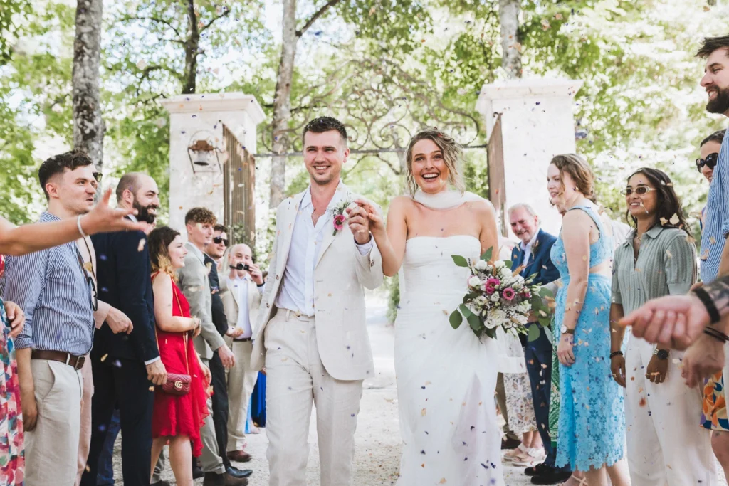 Sortie de cérémonie laïque pour les mariés au château Sainte-Foy d'Anthe en Lot-et-Garonne, sous les confettis et une haie d'honneur de leurs invités.