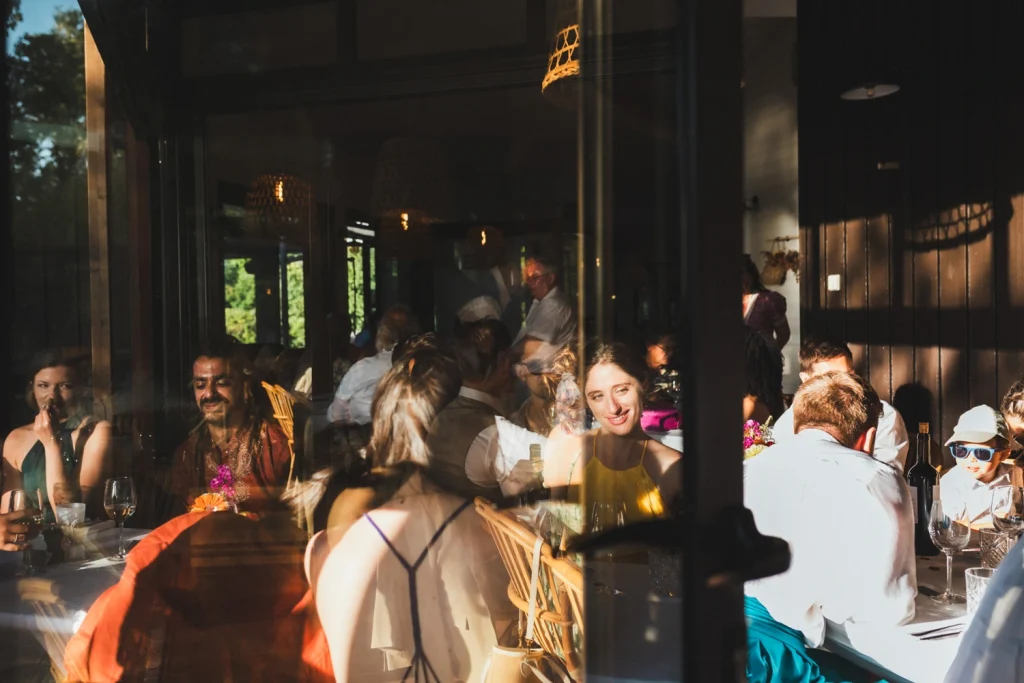 Scène de repas avec les invités qui passent à table alors que la lumière du jour décline, lors d'un mariage à Bordeaux.