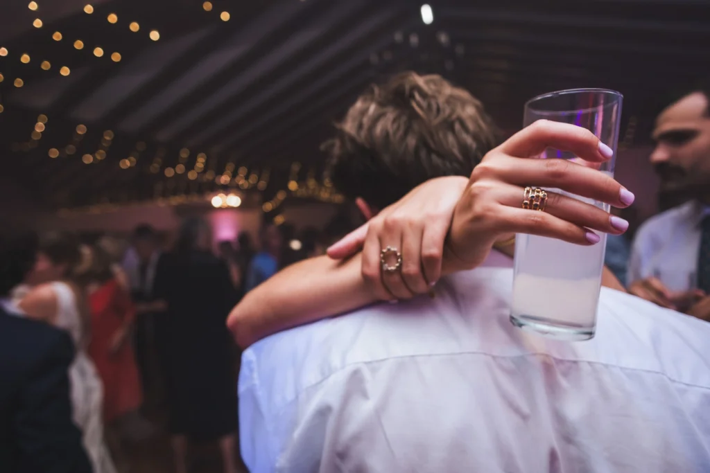 Mains qui enlacent un invité tout en tenant un verre de cocktail, lors d'un mariage au Pays Basque.