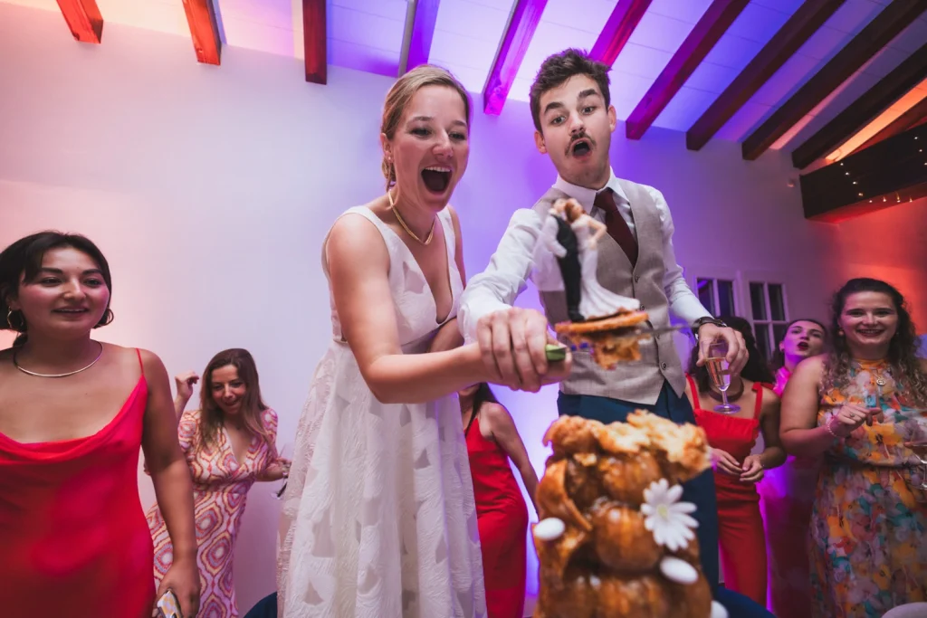 Les mariés découpent la pièce montée avec énergie lors de leur repas de mariage au Pays Basque.