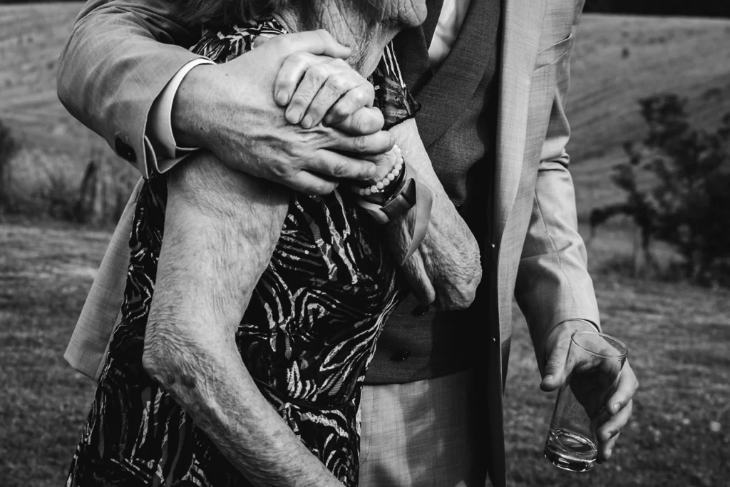 Détail de la main du marié qui enserre celle de sa grand-mère pendant le cocktail de mariage au Pays Basque au domaine Etxezahar.