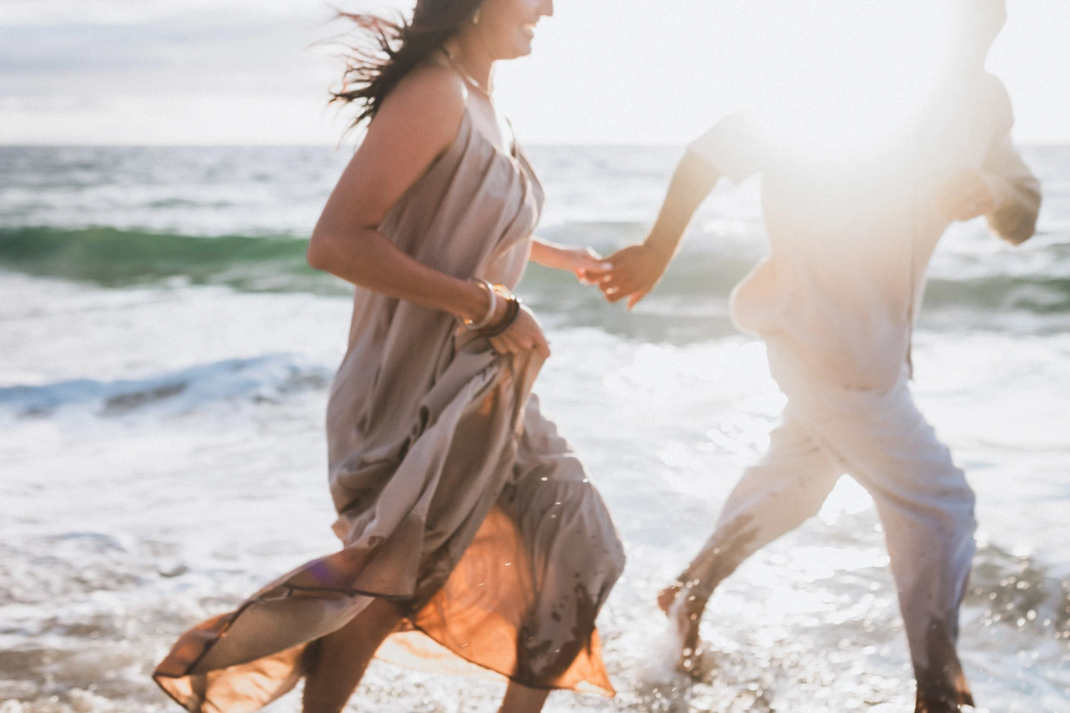 Un couple court sur la plage en longeant l'océan dans le soleil couchant, par une photographe mariage landes