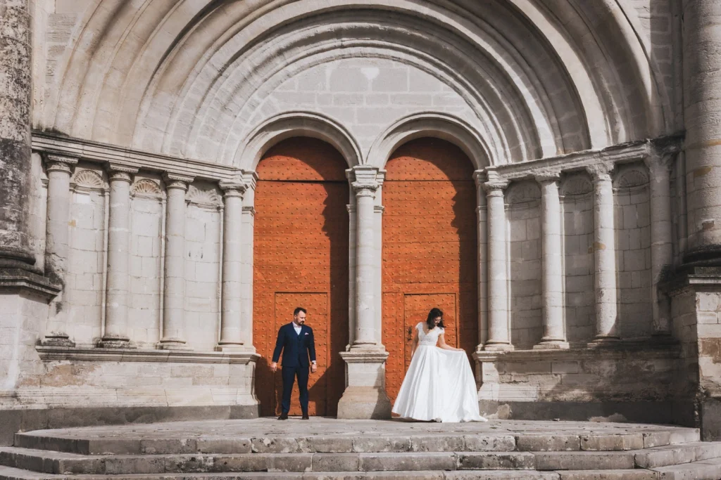 Devant la cathédrale de Lescar, les mariés prennent la pose face à une photographe mariage Landes.