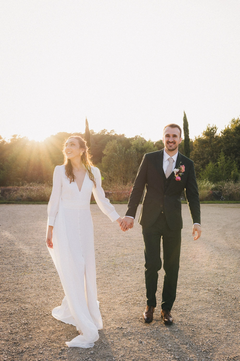 Les mariés se tiennent par la main en marchant dans les derniers rayons du soleil dans les Landes