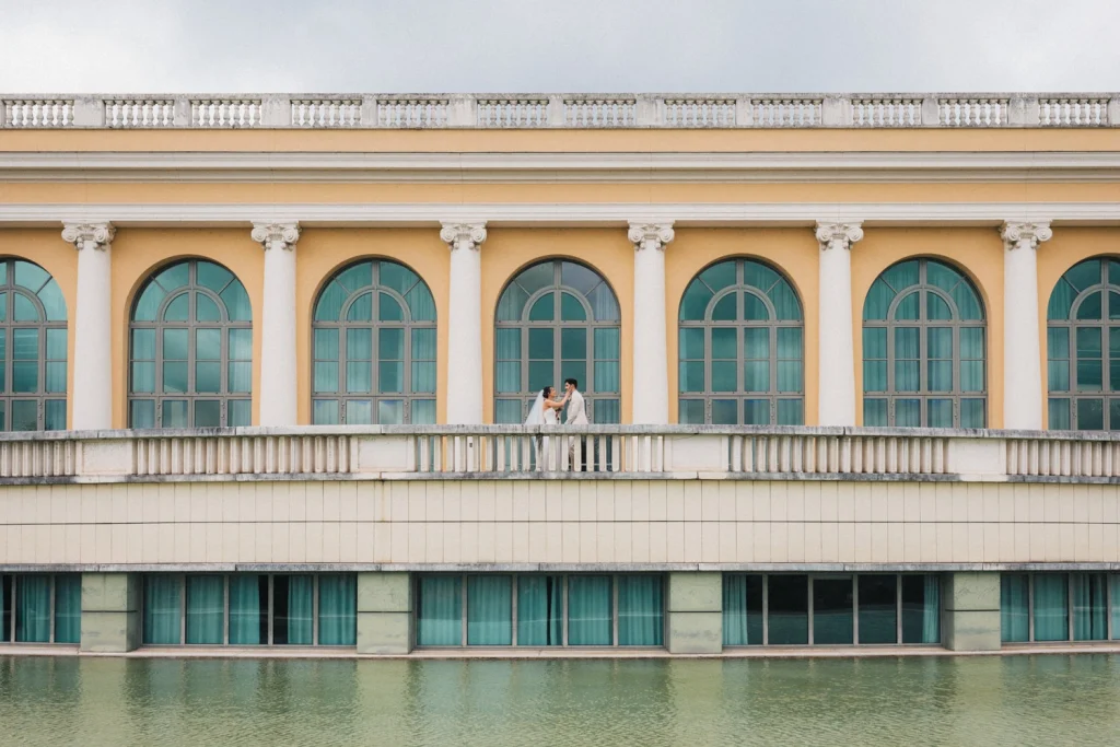 Face à un bâtiment à l'architecture graphique et colorée, le couple se découvre pour la première fois en habits de mariés.