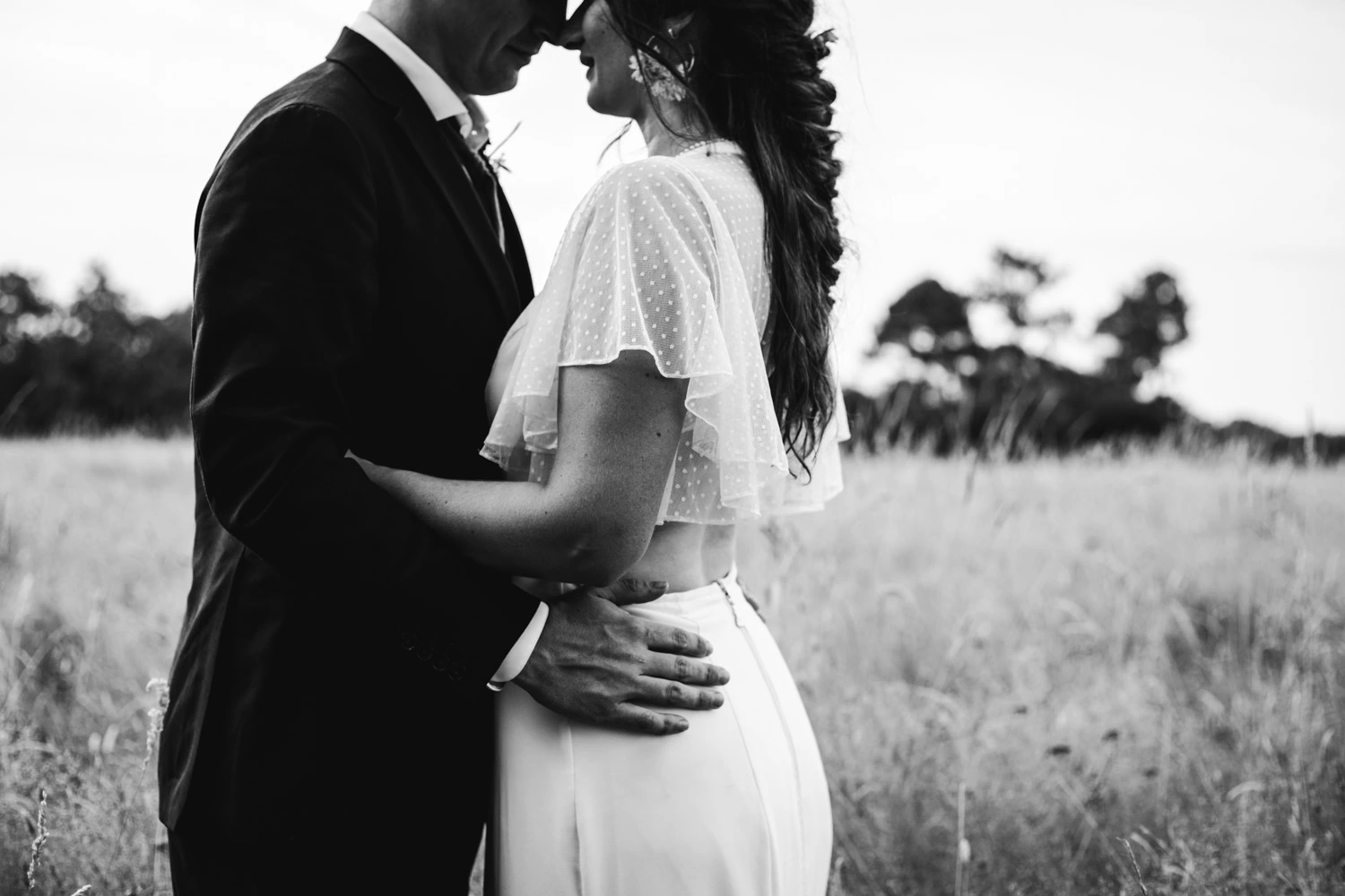 Les mariés se tiennent front contre front dans un champ en face du domaine Le Herre en Gironde, par une photographe du Sud Ouest
