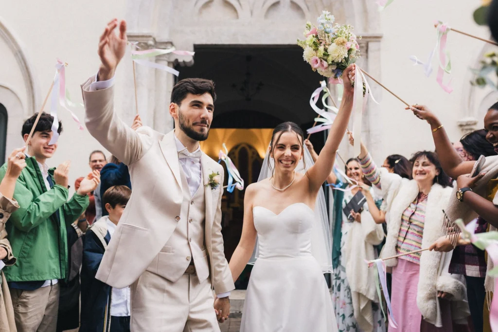 Sortie de cérémonie religieuse sous les rubans et les applaudissements pour les mariés, immortalisée par une photographe mariage Landes