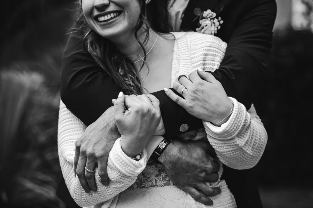 Détail des bras et mains des mariés enlacés pendant leur séance couple à Pau