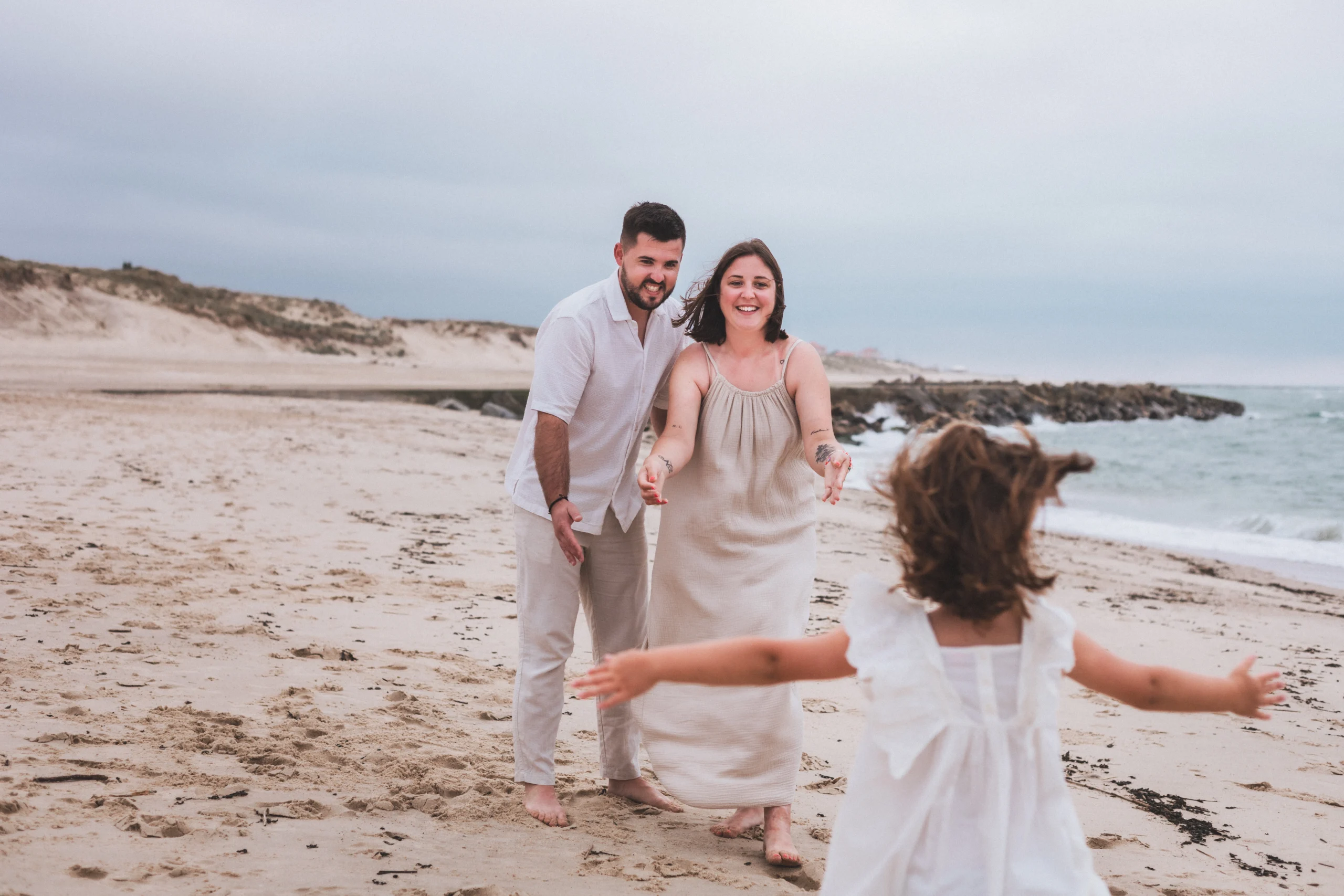 Une petite fille court se jeter dans les bras de ses parents, sur une plage en Gironde