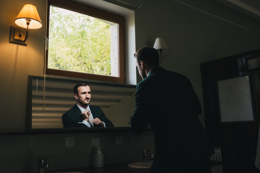 Le marié ajuste sa tenue une dernière fois dans le miroir de sa chambre
