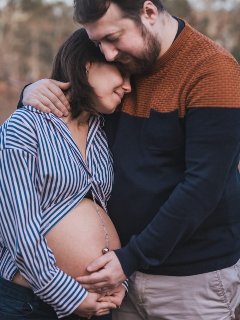 Les futurs parents s'enlacent tendrement, une main posée sur le ventre rond de la femme enceinte, immortalisé par une photographe famille landes