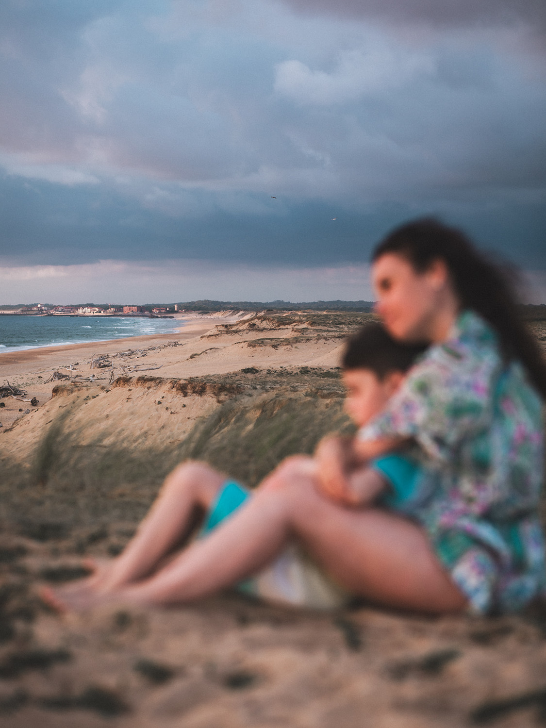 Une mère enlace son fils sur la dune en contemplant l'océan, immortalisée par une photographe famille landes