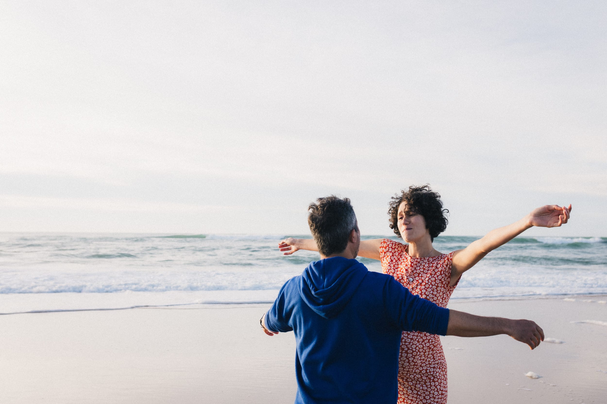 Les futurs parents tendent les bras pour se serrer dans les bras l'un l'autre au bord de l'océan à Lacanau