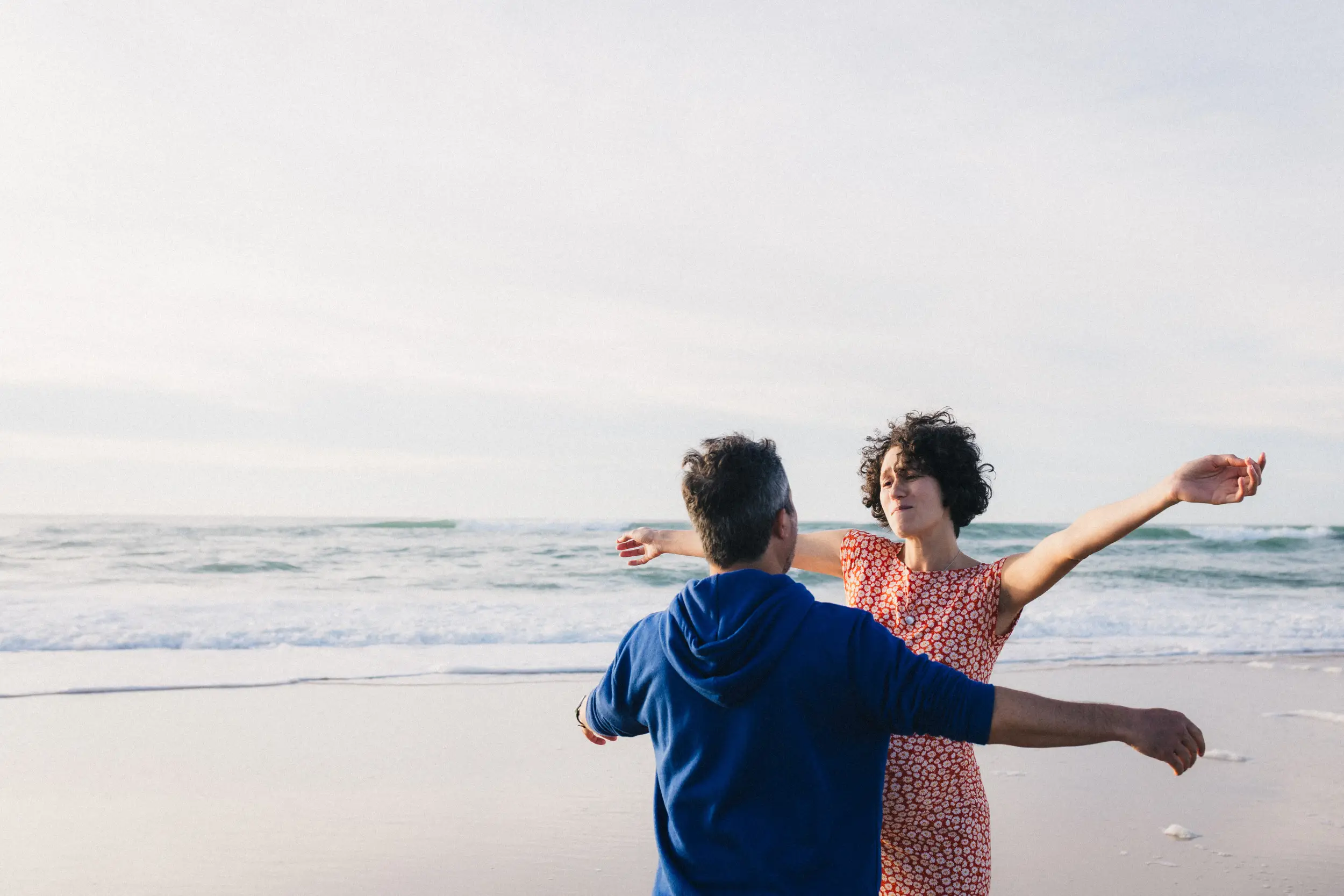 Les futurs parents tendent les bras pour se serrer dans les bras l'un l'autre au bord de l'océan à Lacanau