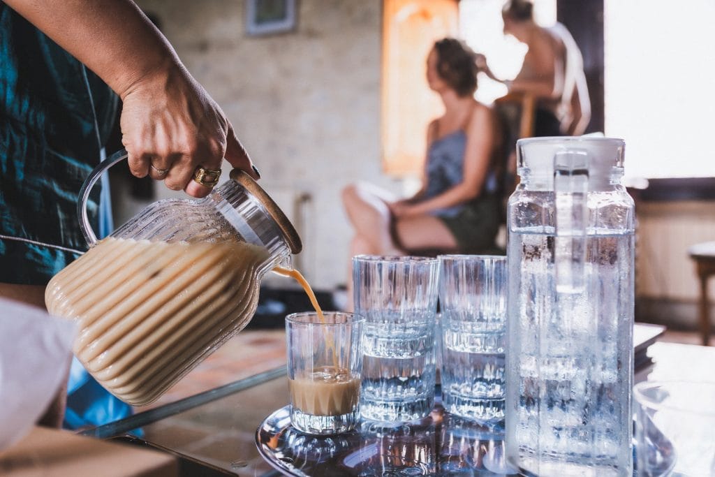 Une demoiselle d'honneur verse du café glacé dans les verres pendant que la mariée se fait coiffer