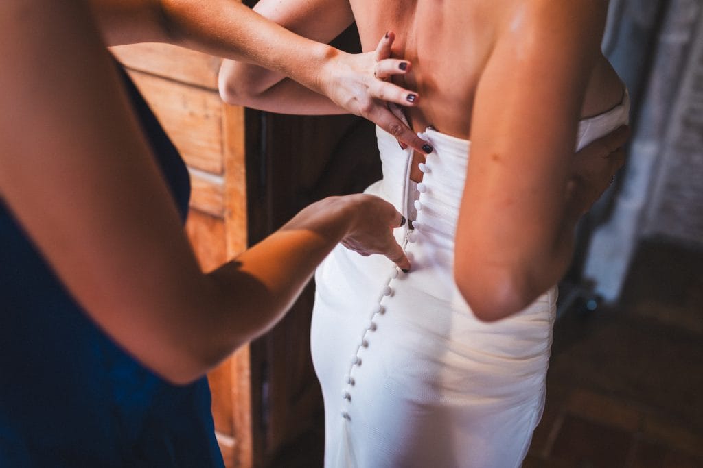Détail du dos de la robe de la mariée, boutonnée par les mains de sa soeur