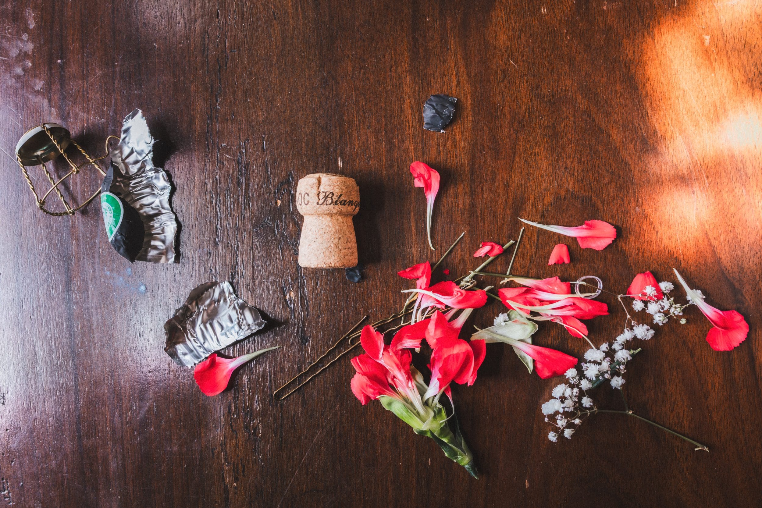 Détail des déchets de la matinée, bouchon de champagne, épingles à cheveux, pétales de fleur, posés sur une table