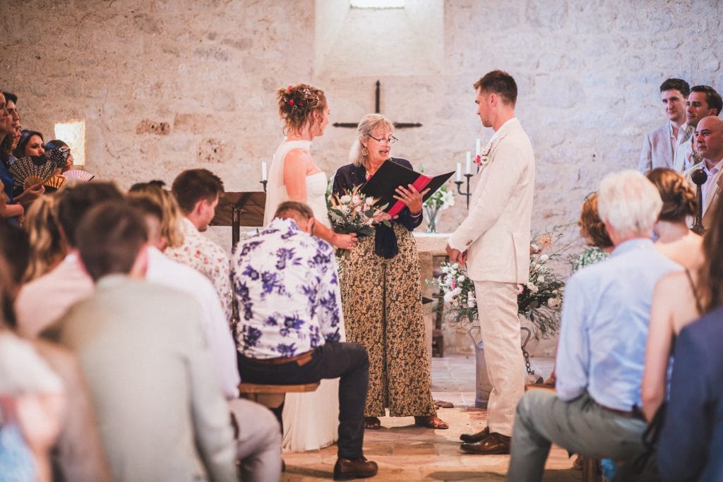 Les mariés se tiennent face à face durant leur cérémonie de mariage au château sainte-Foy