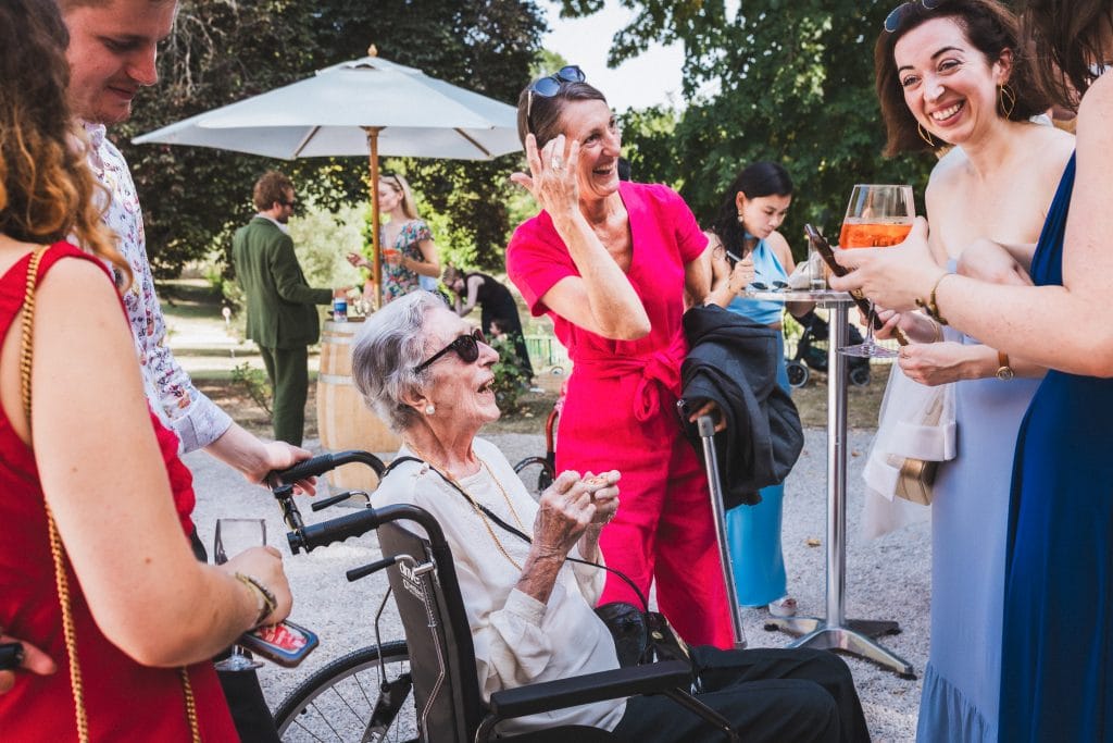 La mère de la mariée et sa grand-mère éclatent de rire, un verre à la main, durant le cocktail