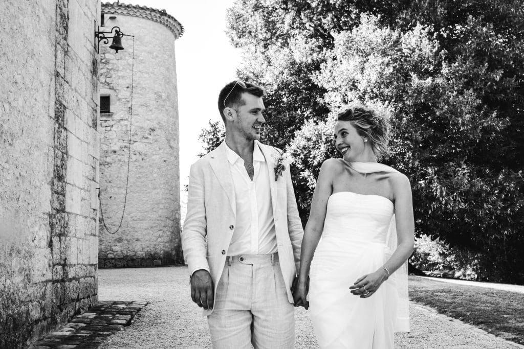 Les mariés marchent main dans la main durant leur séance photo de mariage au château Sainte-Foy
