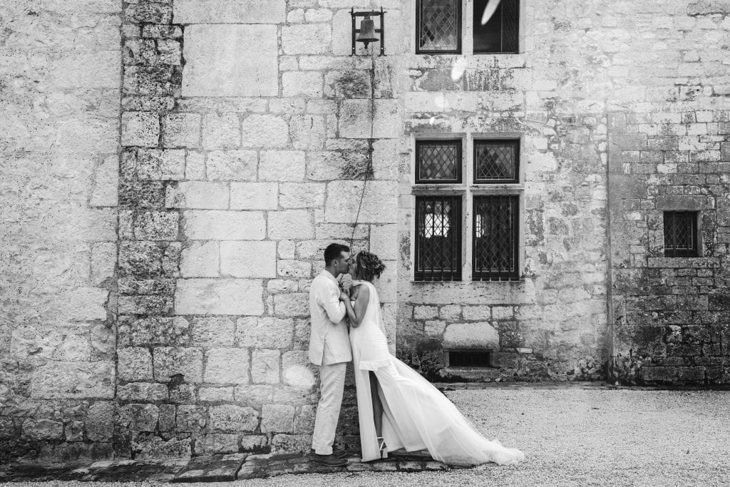 Les mariés s'embrassent en sonnant la cloche lors de leur mariage au château Sainte-Foy