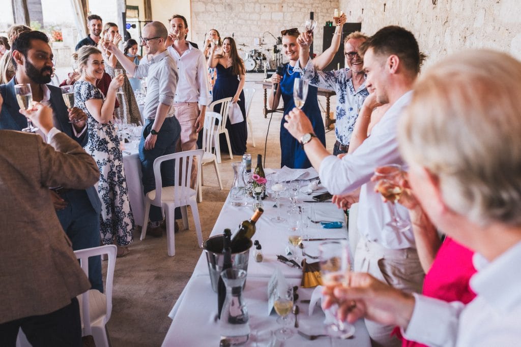 Les invités lèvent leurs verres pour trinquer à la santé des mariés lors de leur repas de mariage