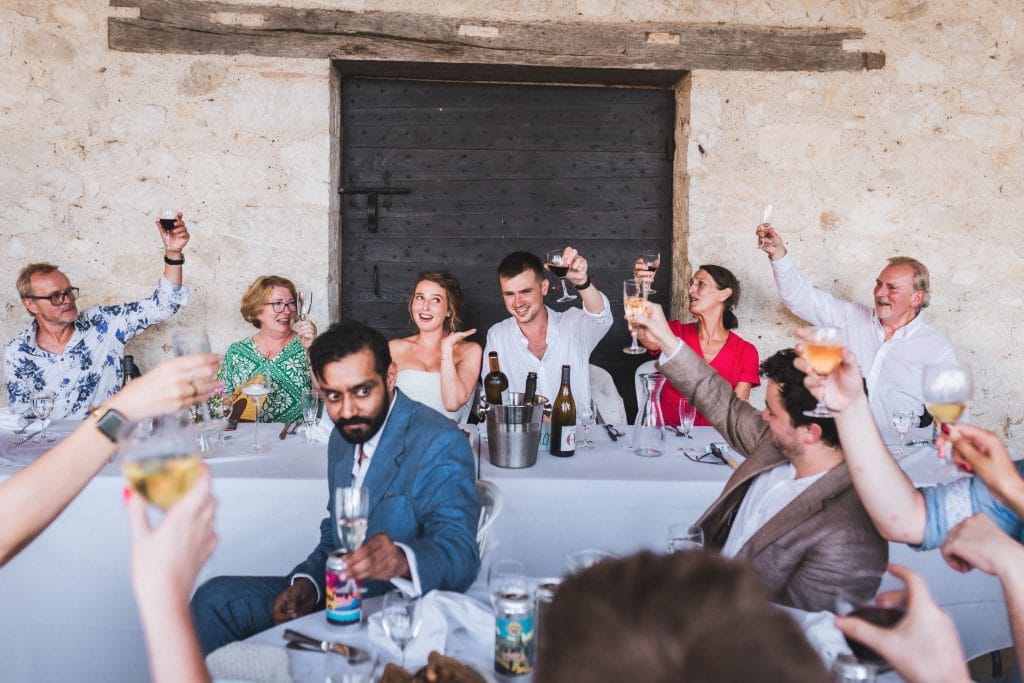 Les invités et les mariés lèvent leurs verres pour trinquer lors de leur repas de mariage