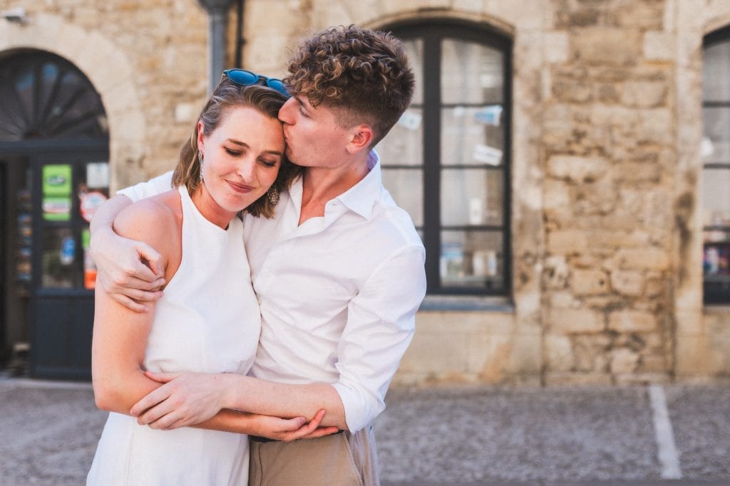 Le petit frère de la mariée, arrivé en retard à la cérémonie, prend sa soeur dans ses bras et lui embrasse la tempe