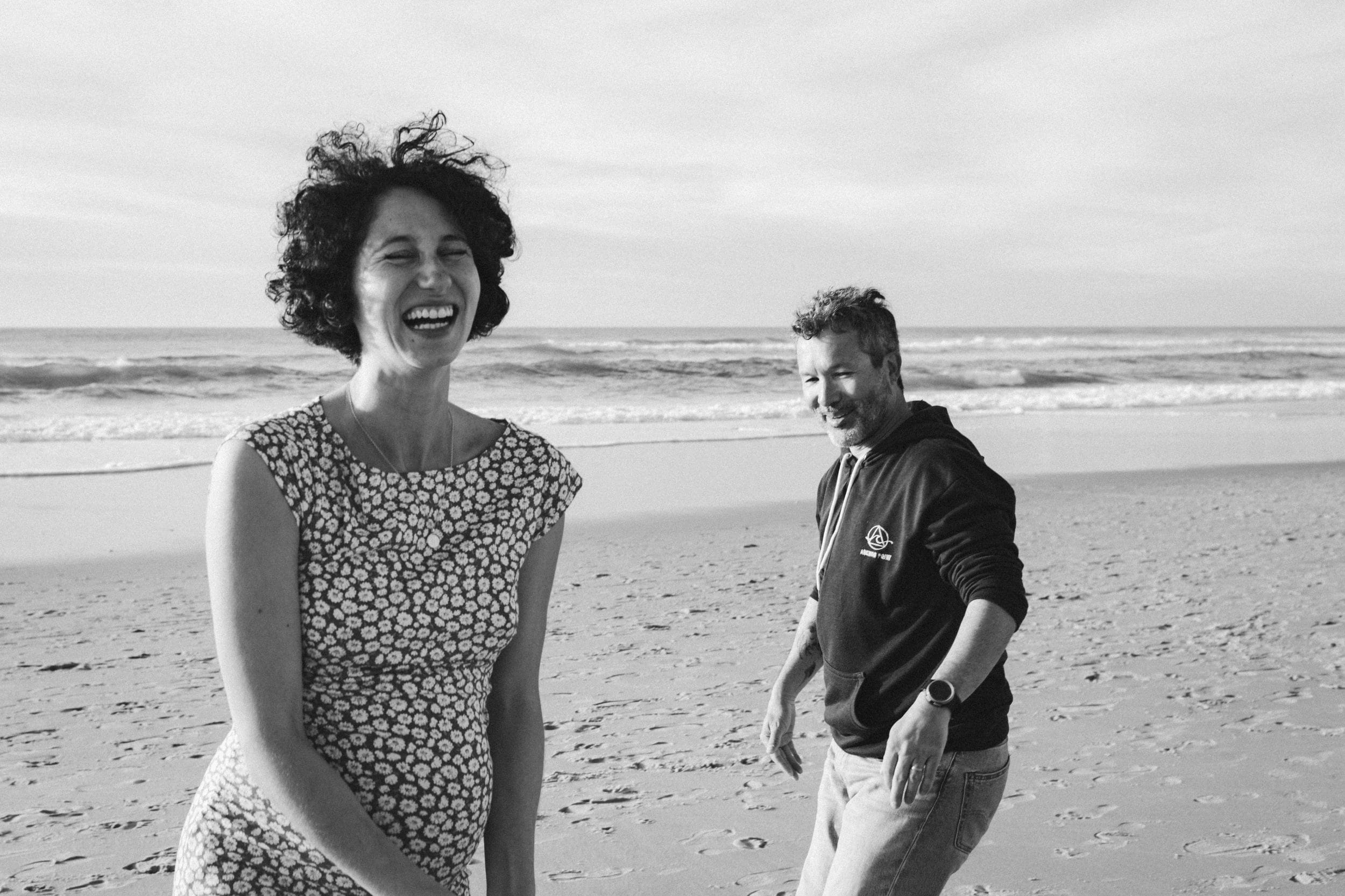 Les futurs parents rient aux éclats sur la plage à Lacanau