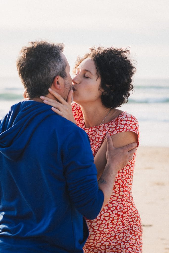 Les futurs parents s'embrassent tendrement lors de leur séance grossesse à Lacanau