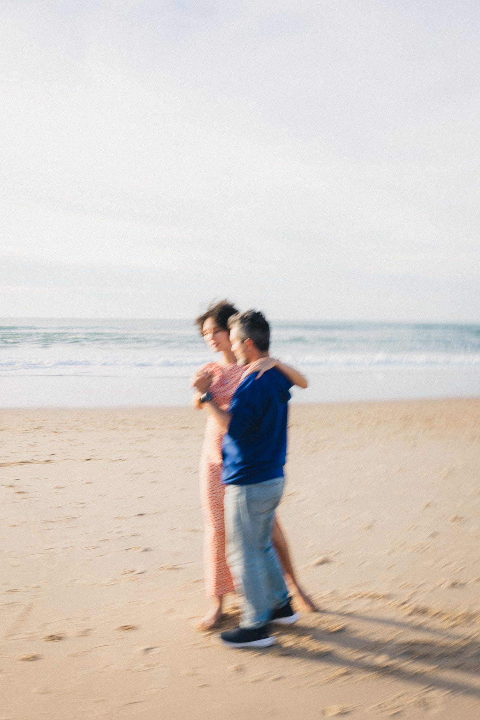 Flou artistique de nos deux futurs parents en train de valser sur la place lors de leur séance grossesse à Lacanau