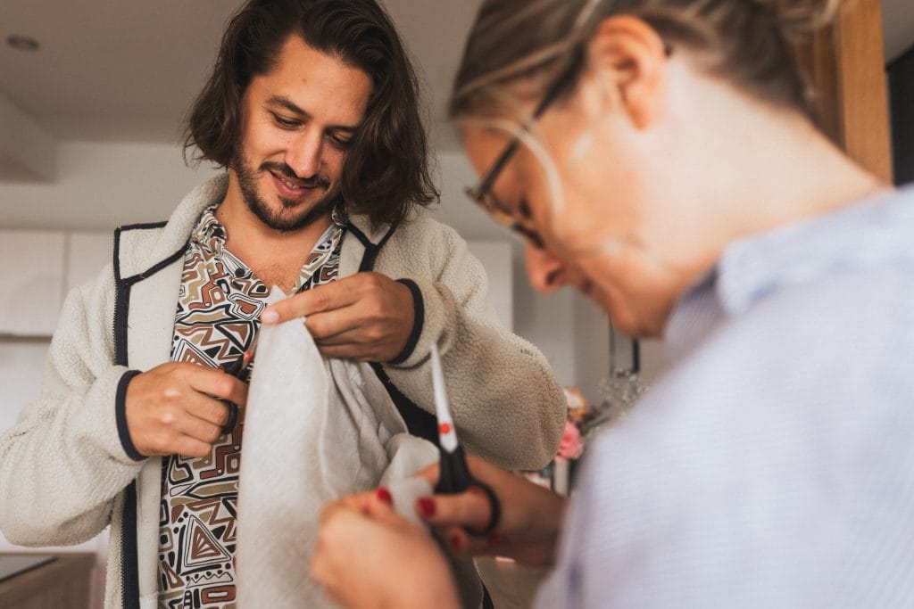 Les témoins coupent un morceau de fil qui dépasse d'une veste de costume en prévision du mariage au Pays Basque